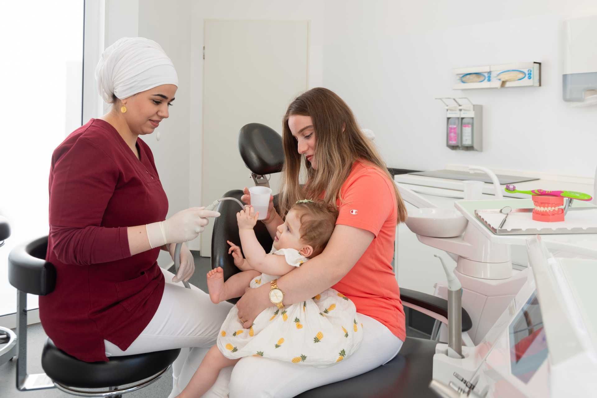 Eine Frau sitzt mit einem Baby in einem Zahnarztstuhl