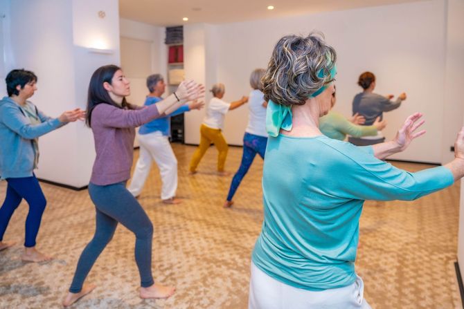 Des personnes participent à un cours de qi gong dans un studio lumineux.