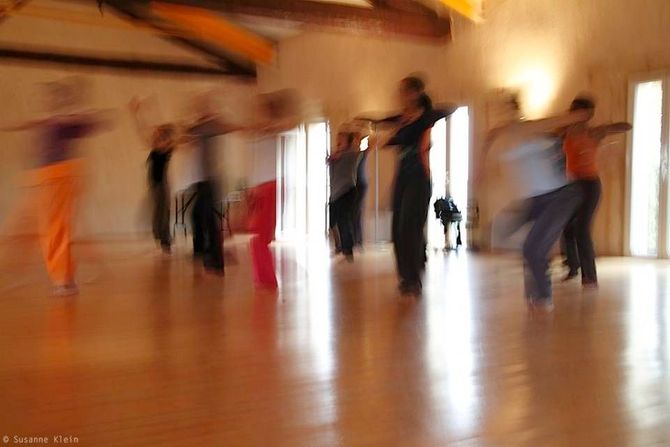 Des personnes floues dansent dans un studio à l'éclairage chaleureux et au parquet ciré
