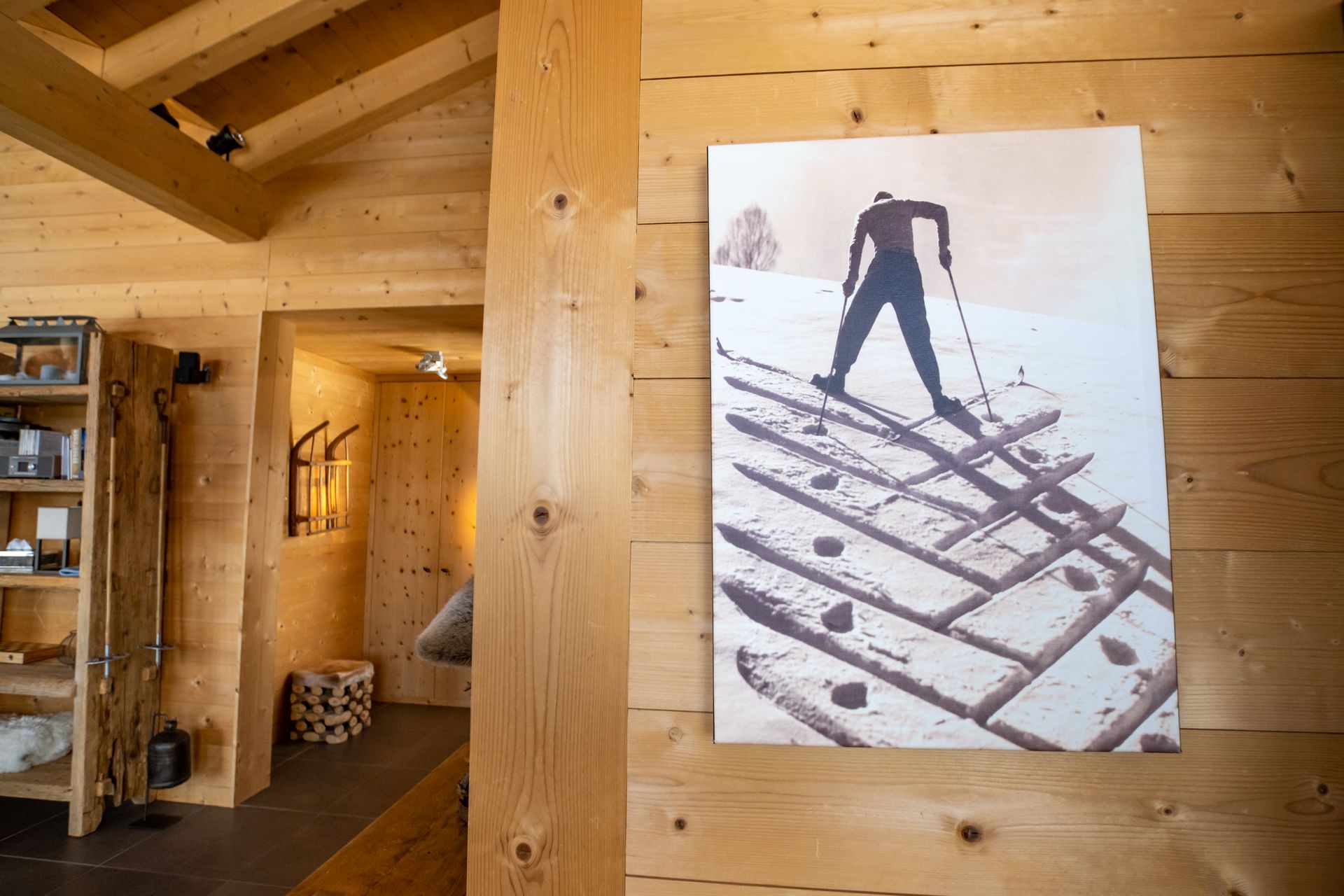 Holzvertäfeltes Interieur mit einem gerahmten Foto eines Skifahrers an der Wand; Türrahmen und Regale sind ebenfalls zu sehen.