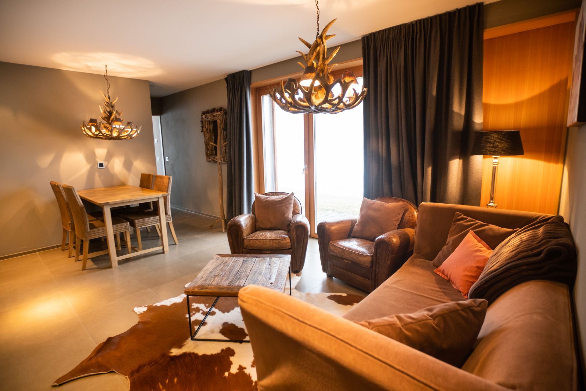 Gemütliches Wohnzimmer mit braunen Ledermöbeln, Holztisch und dekorativer Beleuchtung.