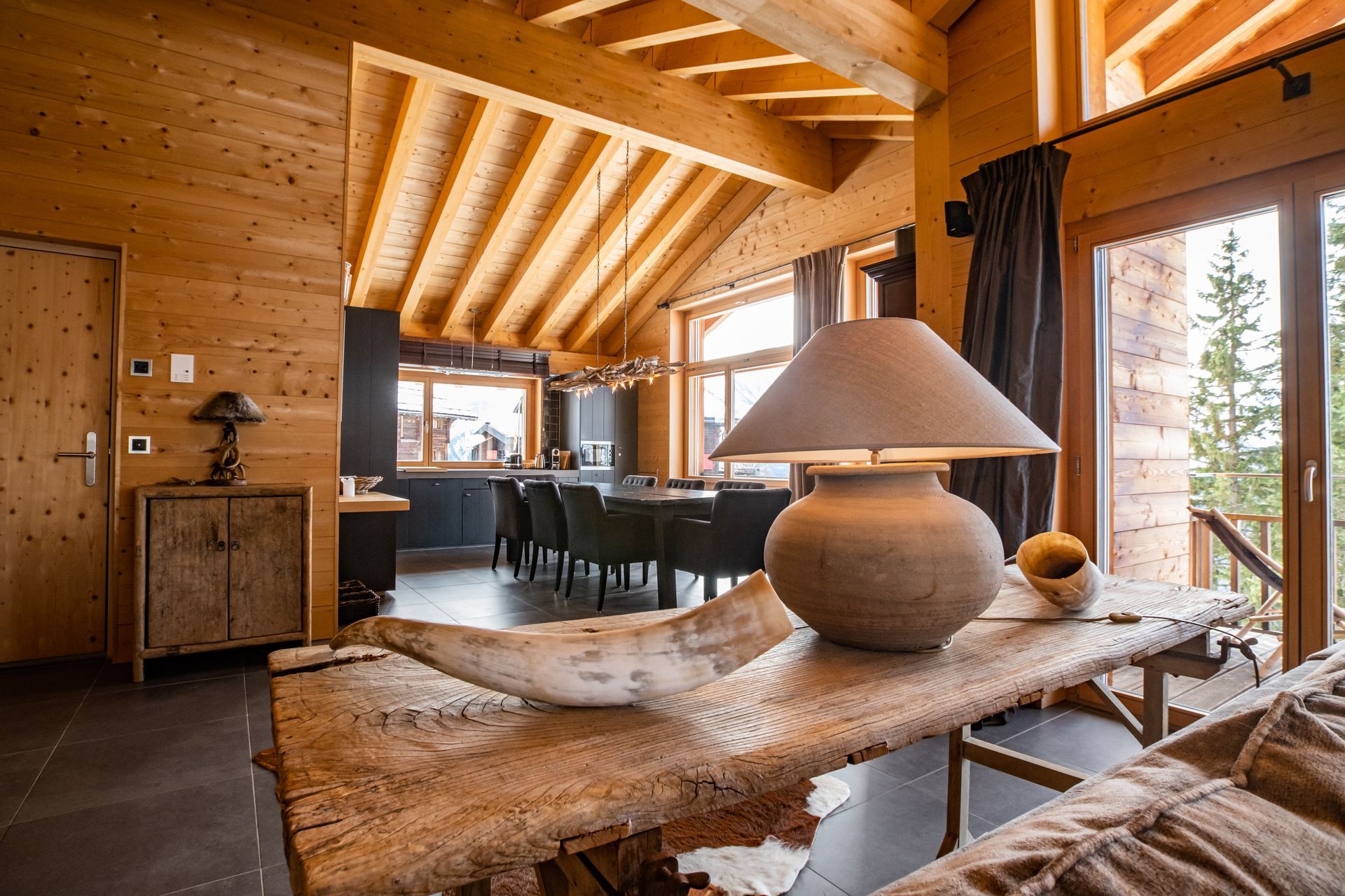 Gemütliches Hütteninterieur mit Holzwänden und -decke, einem Tisch mit Lampe und einem Essbereich.