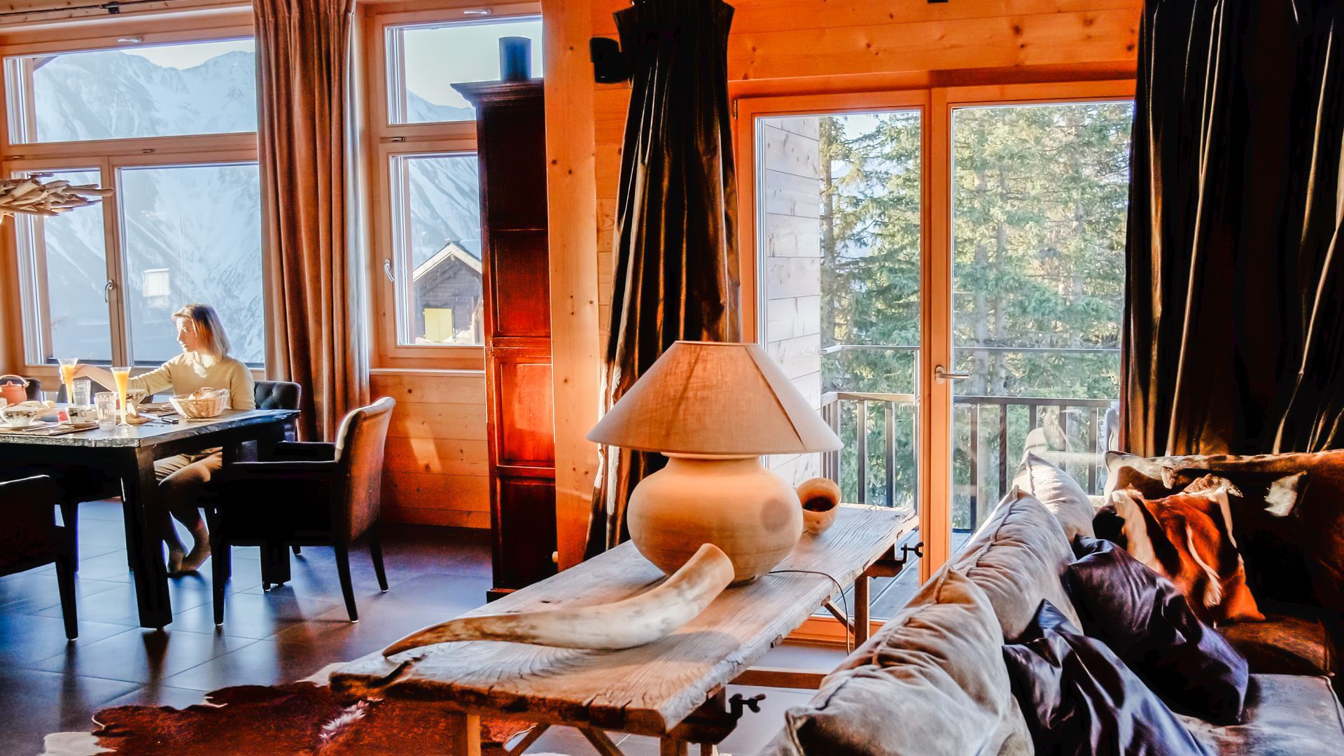 Gemütliches Kabineninterieur mit Esstisch und Balkonblick; Frau sitzt am Fenster.