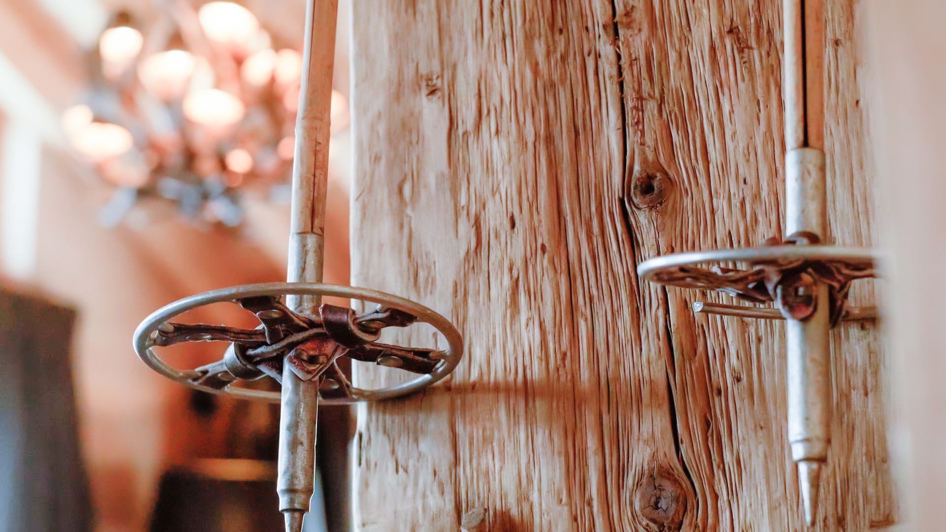 Skistöcke, die an einem verwitterten Holzpfosten im Inneren eines Gebäudes befestigt sind.