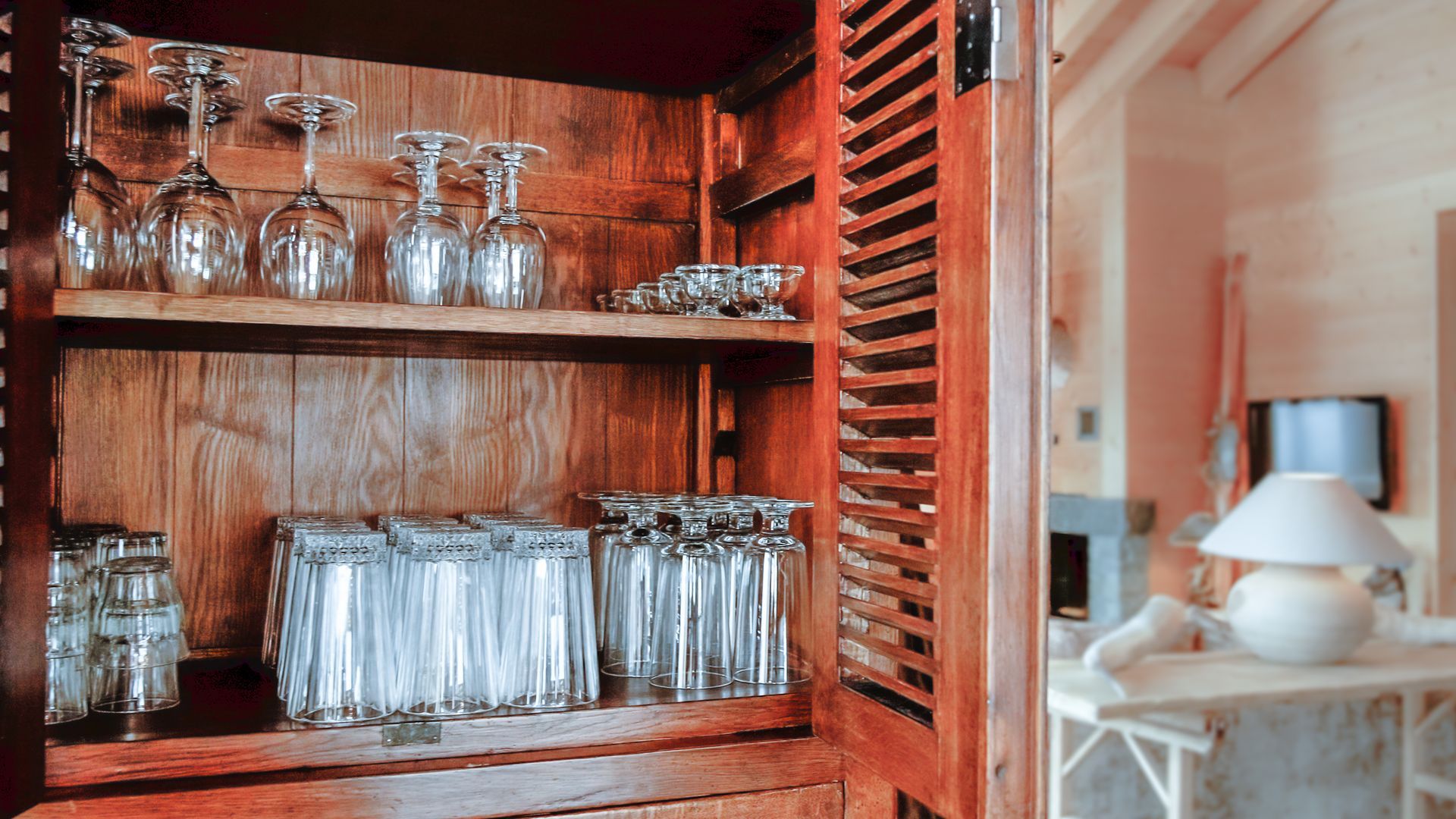 Holzschrank mit Glaseinsatz, offene Tür, im Hintergrund ist das Wohnzimmer sichtbar.