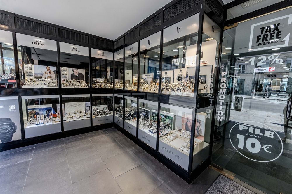 Intérieur de magasin de montres avec vitrines présentant des montres de plusieurs marques.