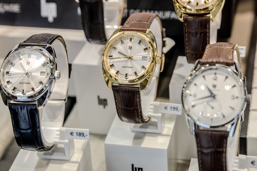 Présentation de montres-bracelets de luxe sur des présentoirs, notamment des modèles en argent, en or et en cuir marron.