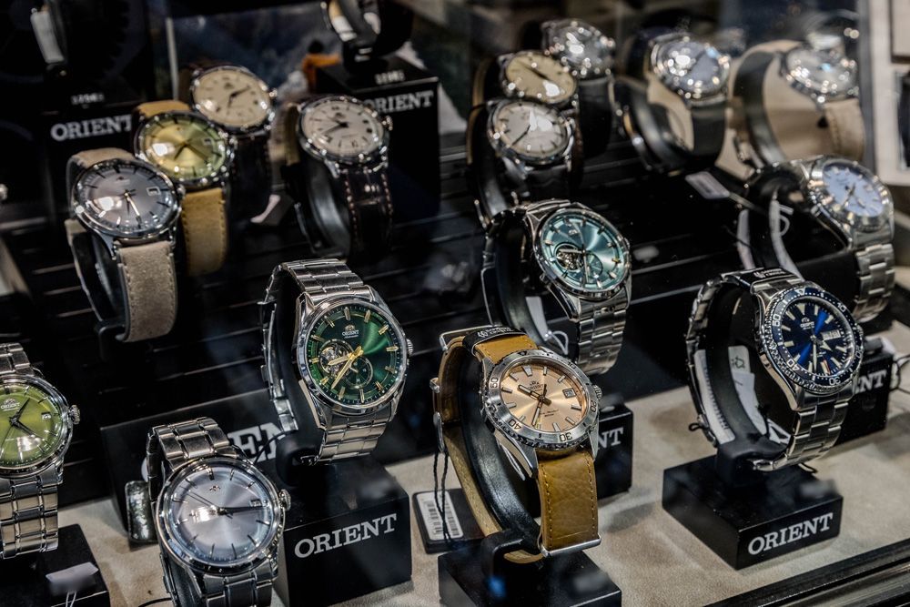 Présentation de montres-bracelets Orient assorties dans une vitrine, avec des accents argentés, noirs, dorés et bleus.