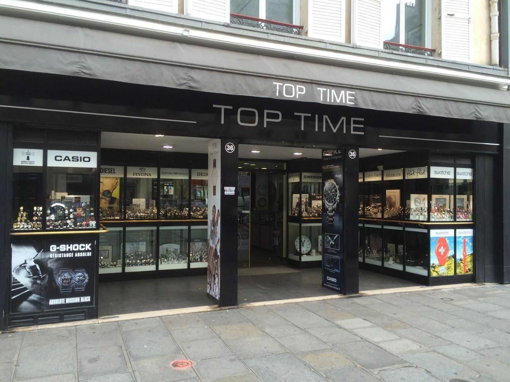Magasin de montres Top Time avec vitrines, auvent noir et porte ouverte.