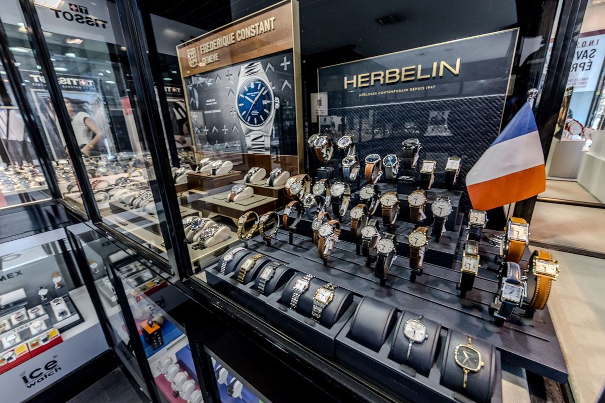 Intérieur d'un magasin de montres avec vitrines. Tissot, Timex et autres marques.