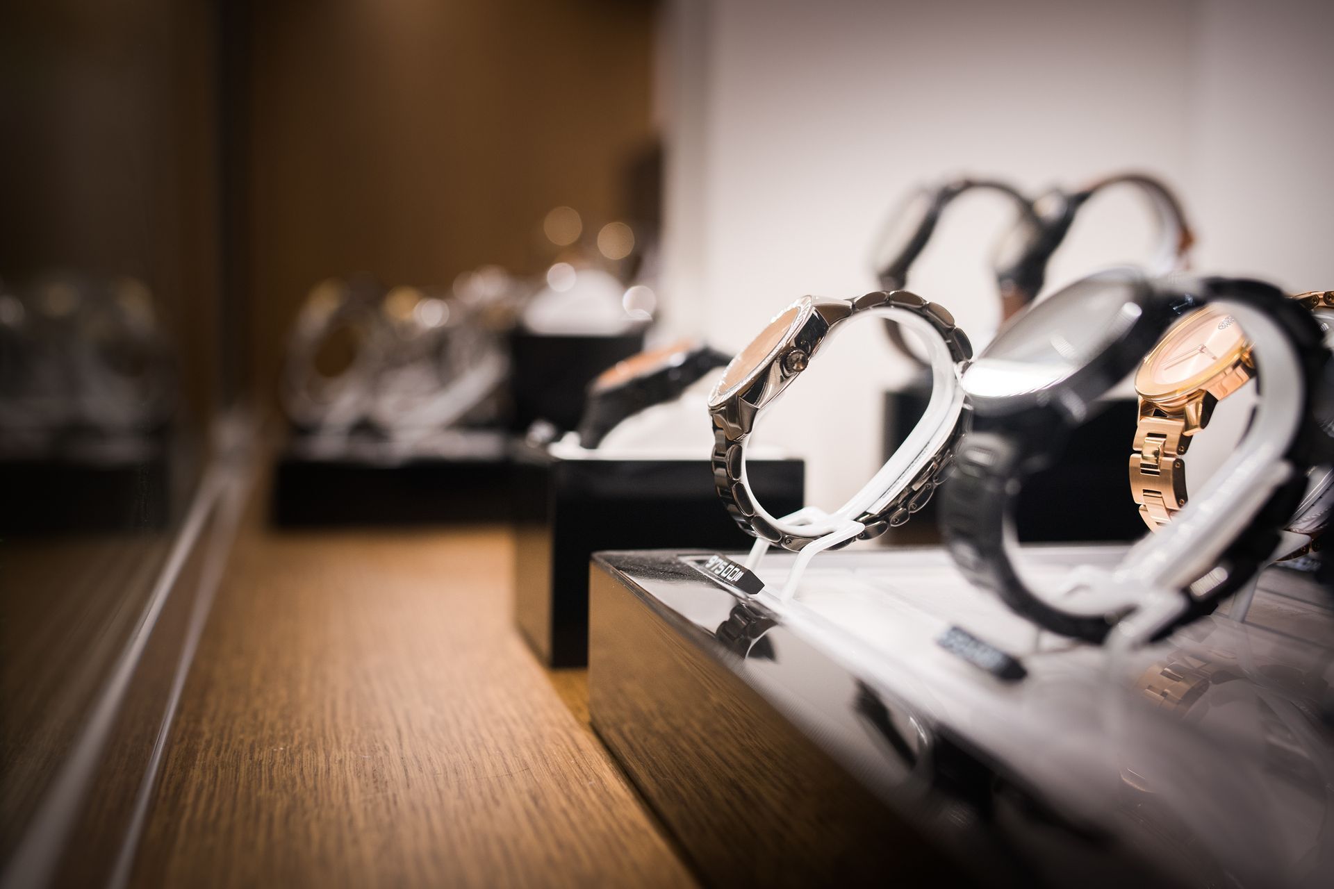 Montres exposées dans un magasin, avec des socles noirs et une étagère en bois chaleureuse.