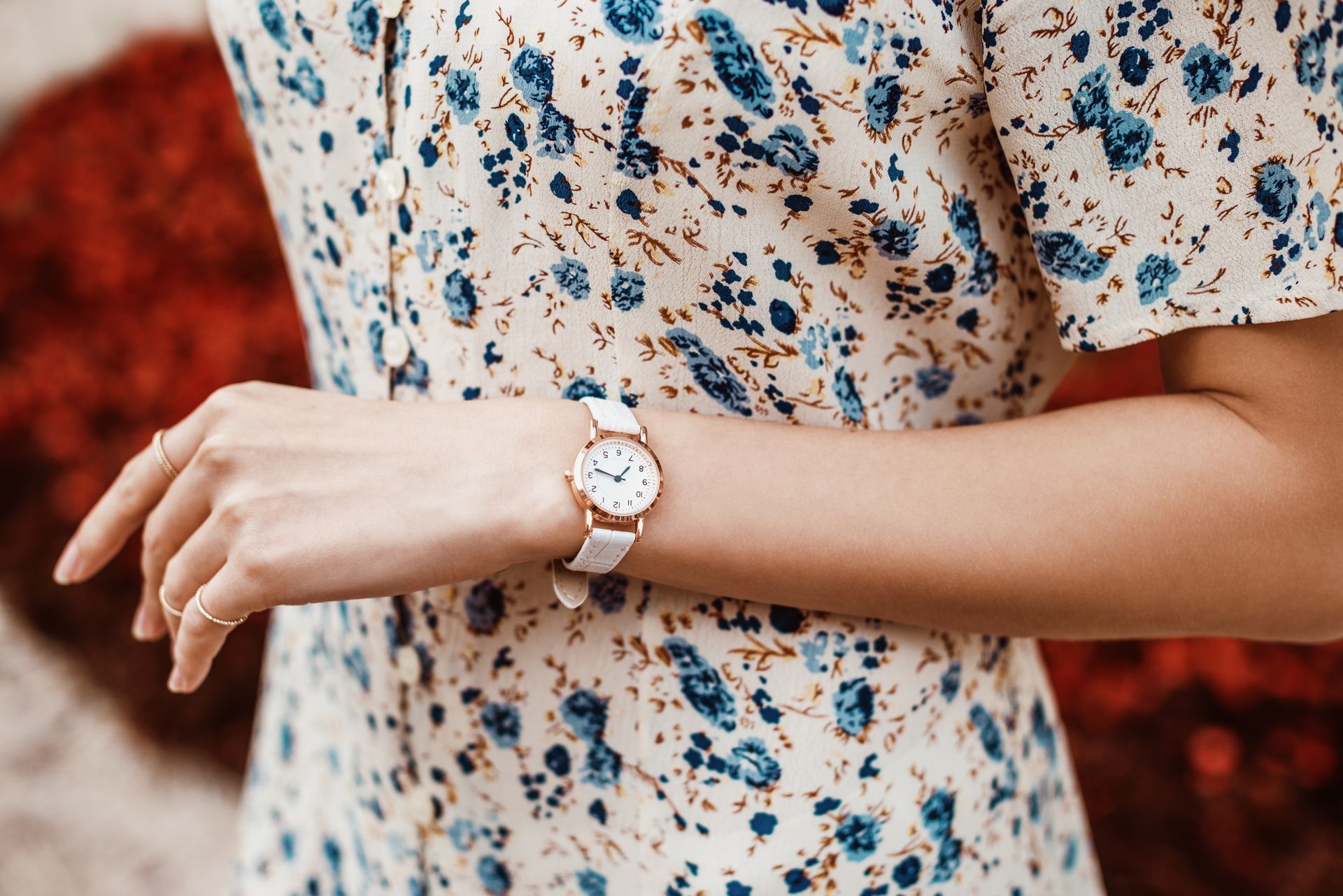 Femme portant une robe fleurie et une montre blanche.