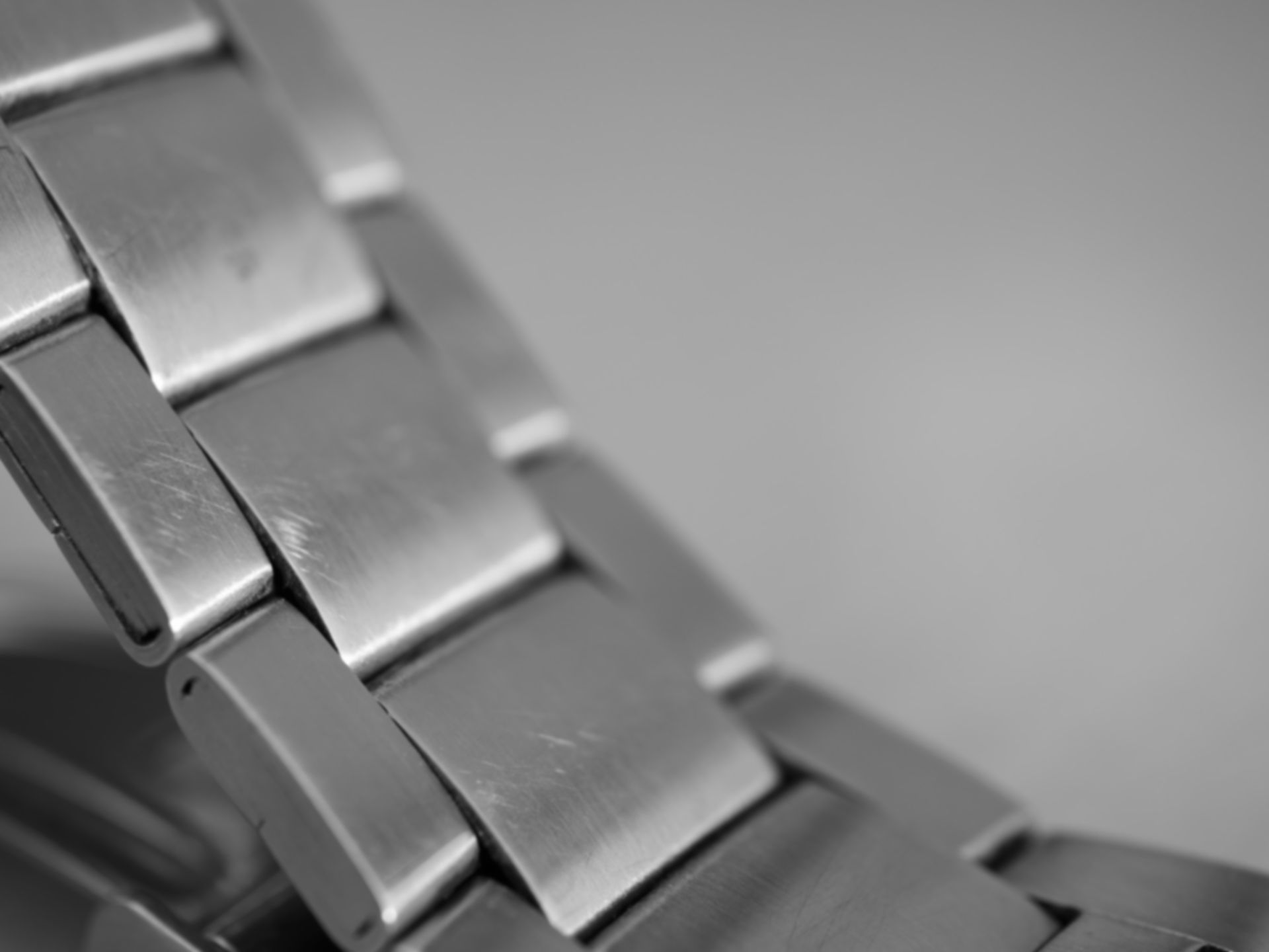Gros plan d'un bracelet de montre-bracelet en argent avec des maillons métalliques rectangulaires inclinés vers le haut à droite.