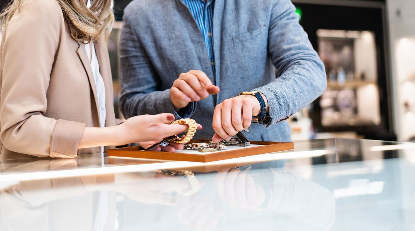 Un homme et une femme dans une bijouterie examinent des bracelets sur un plateau.