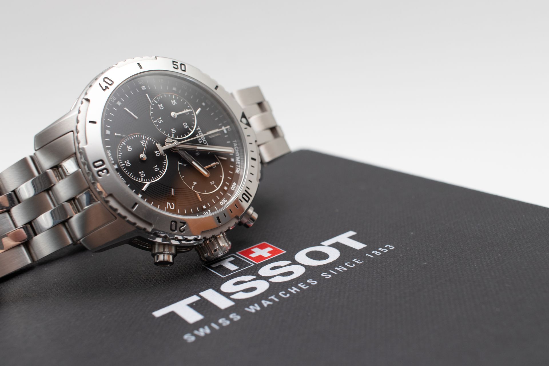 Montre Tissot argentée sur boîte noire, logo de la marque suisse visible.