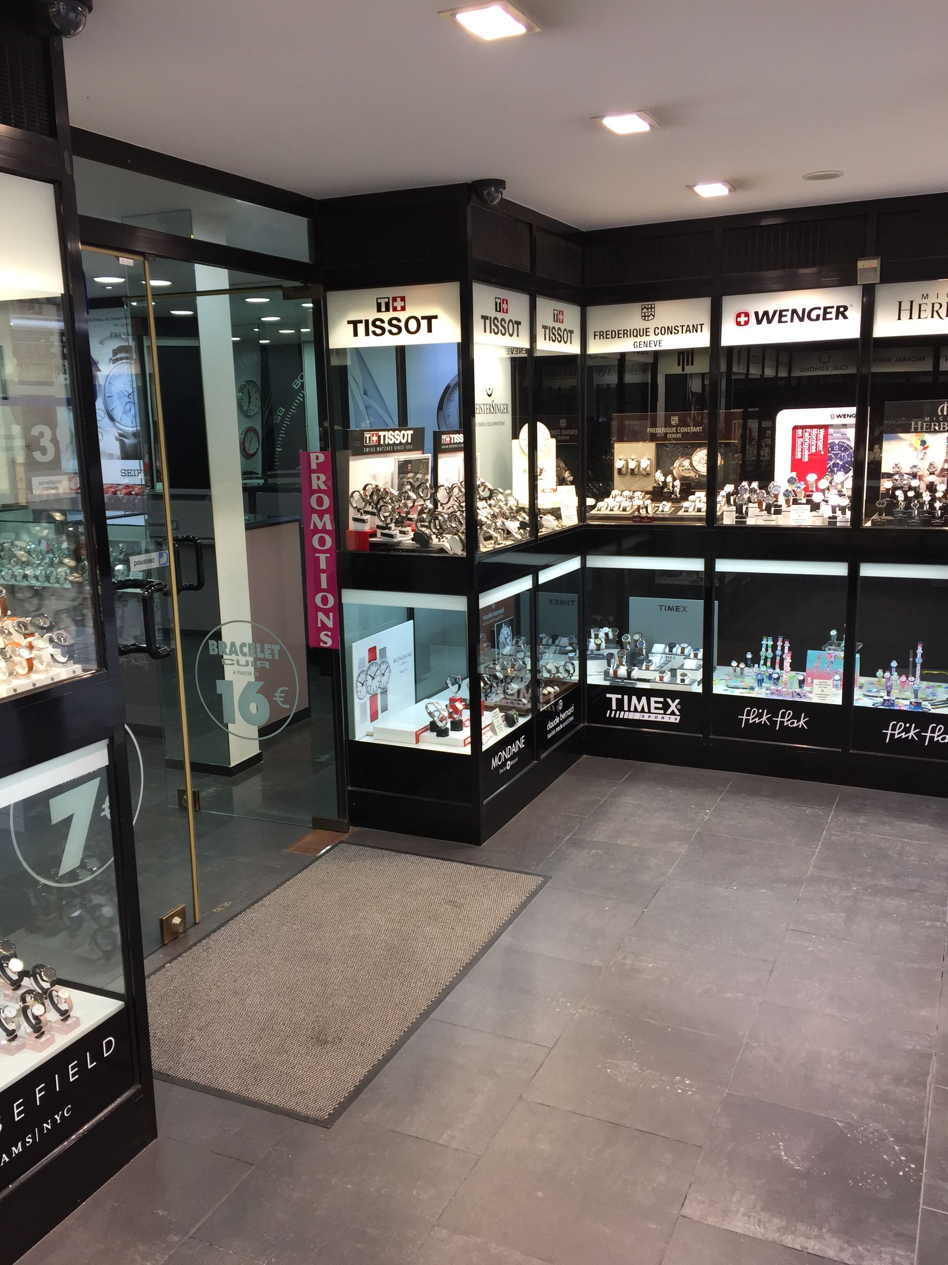 Intérieur d'un magasin de montres avec vitrines. Tissot, Timex et autres marques.