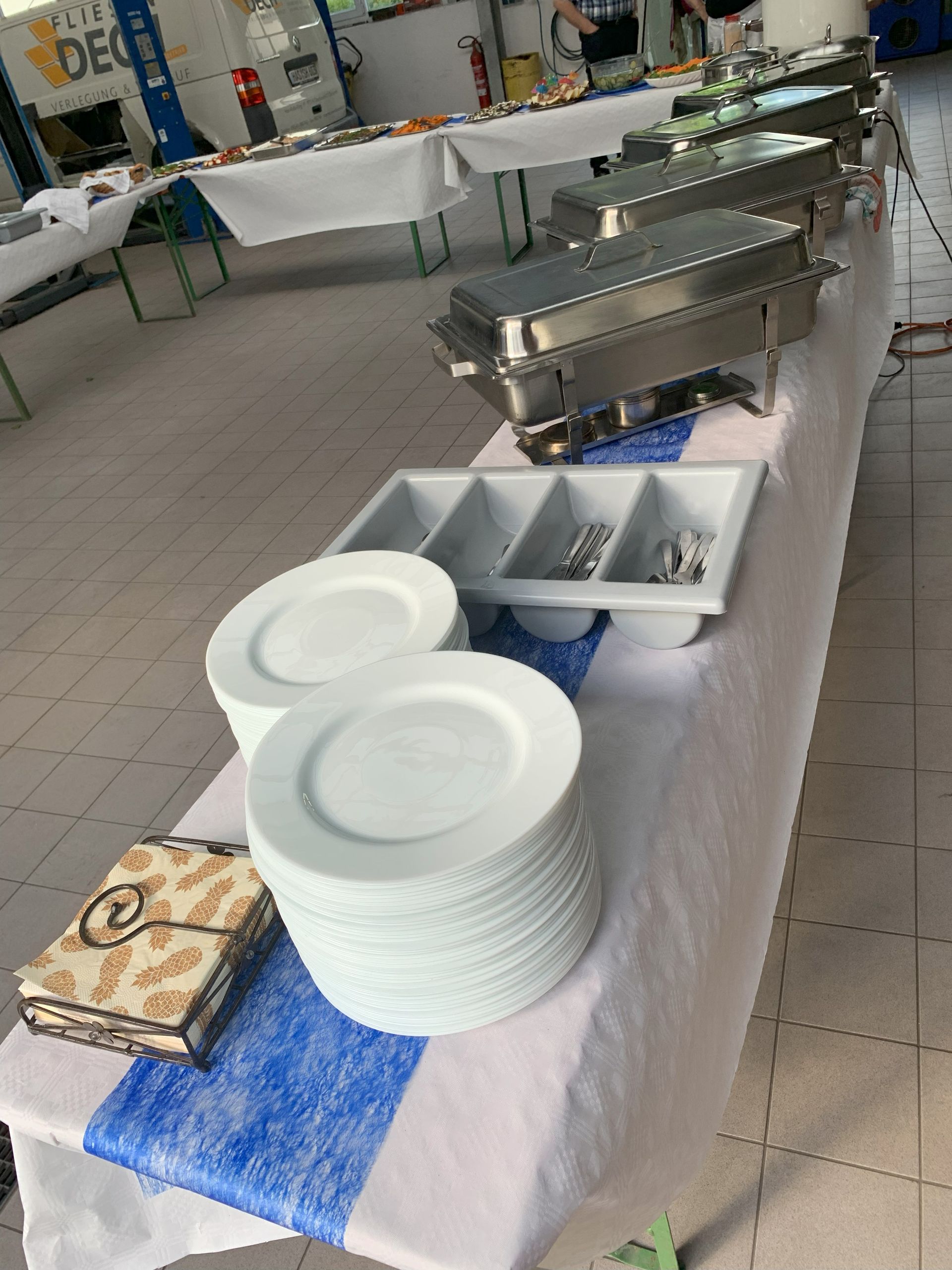 Buffettisch mit Stapeln weißer Teller, Serviergeschirr und Besteck.