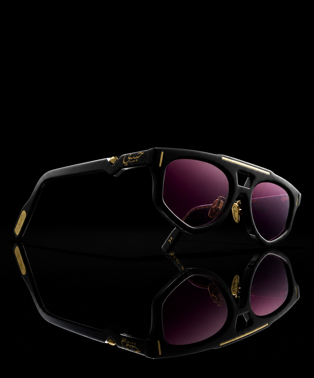 Schwarze Sonnenbrille mit goldenem Streifen oben und rosa-violetten Verlaufsgläsern.