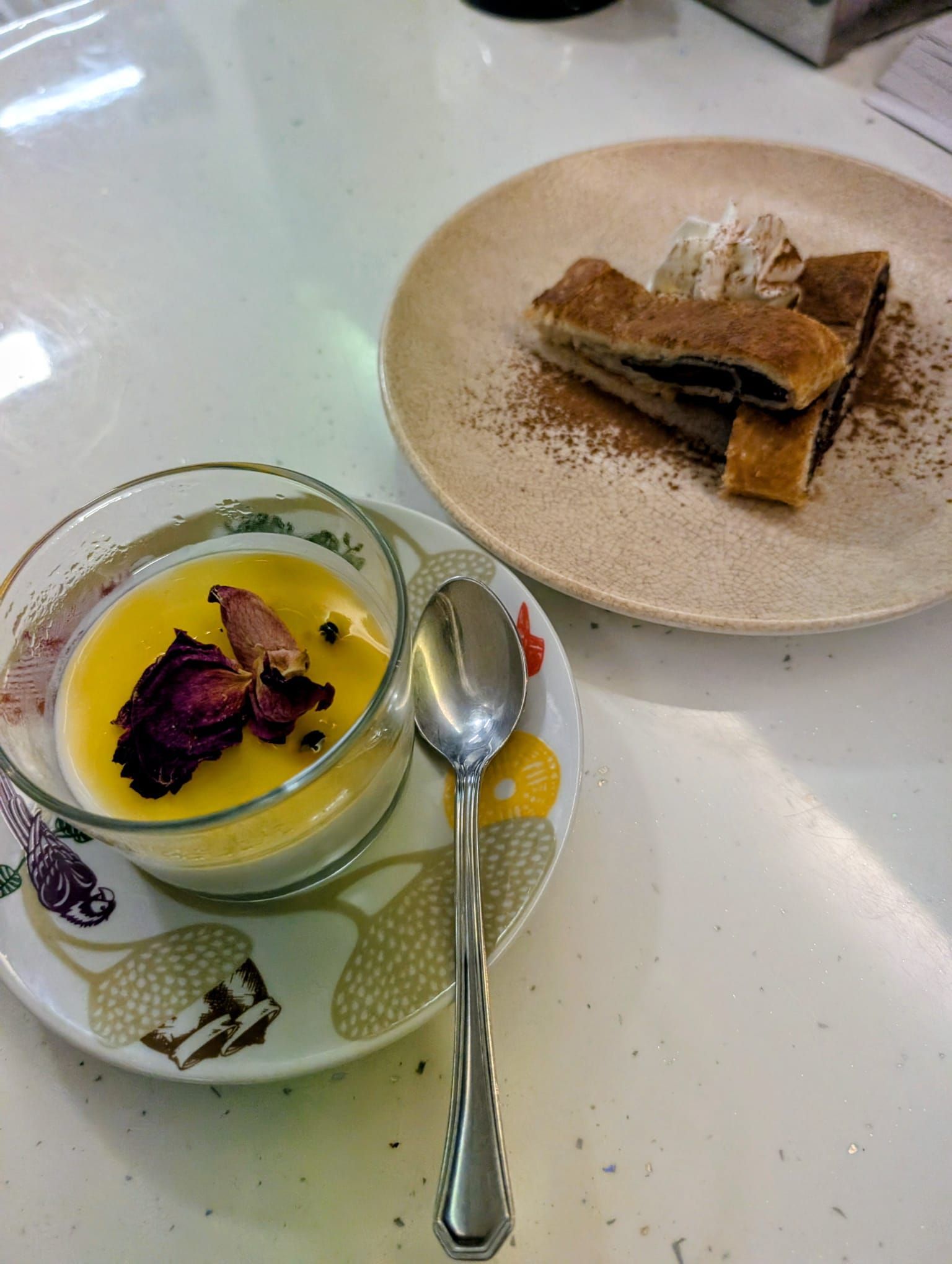 Postre: natillas en vaso, pastel de chocolate en plato, ambos sobre una encimera blanca.