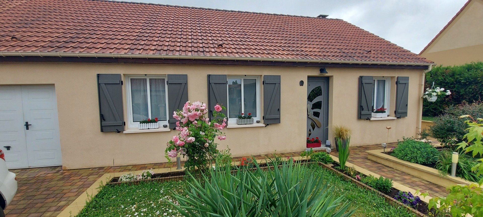 Maison avec crépit jaune et menuiserie blanche et volet de couleur gris anthracite
