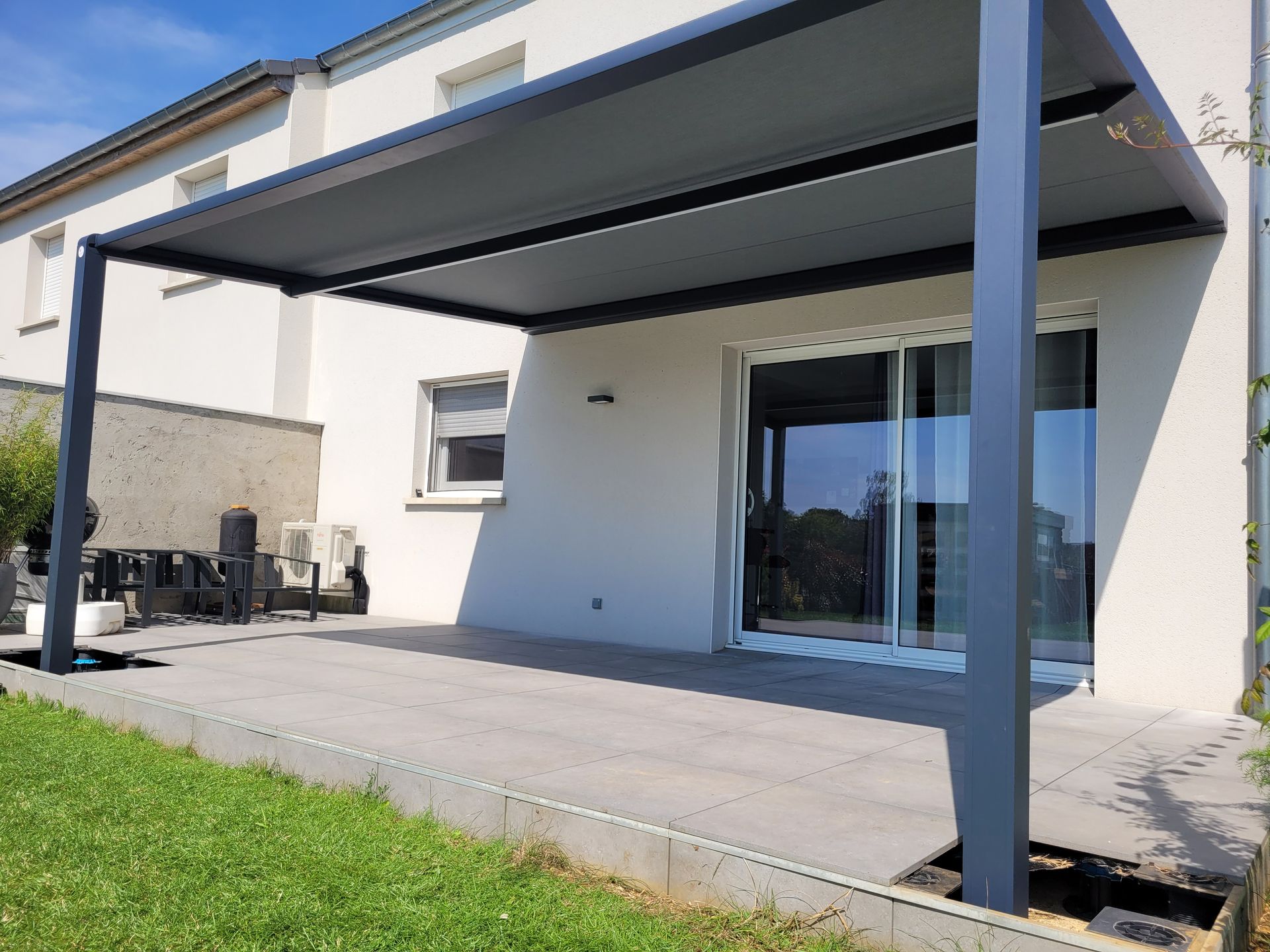 Pergola sombre au dessus d'une porte-fenêtre coulissante donnant sur une terrasse
