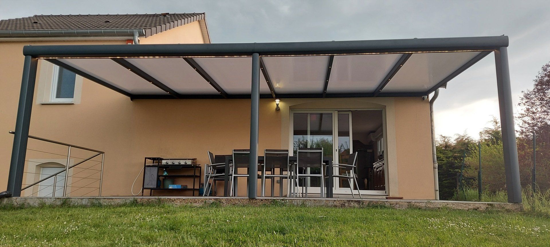 Pergola abritant table et chaisesdevant un jardin