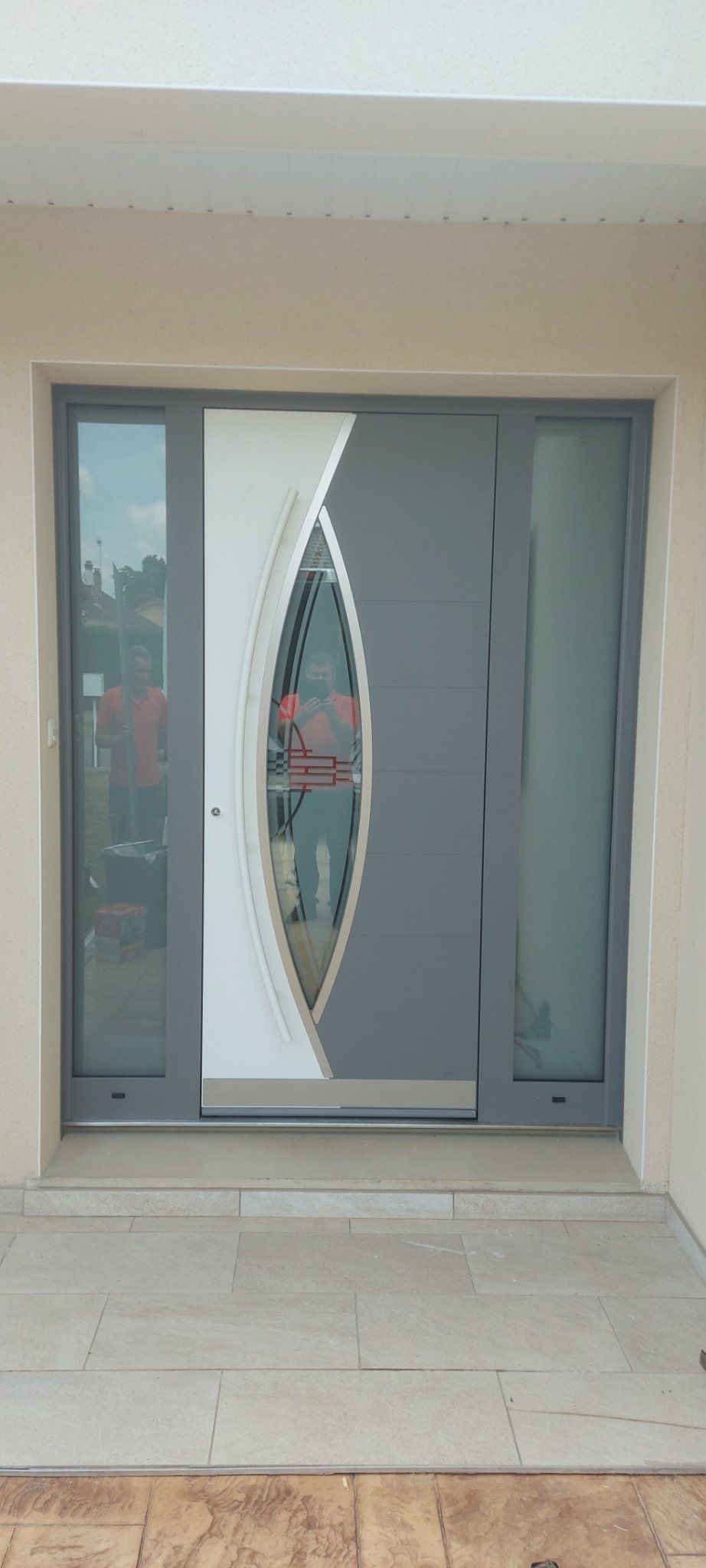 Porte en aluminium de couleur gris clair, dotée de détails géométriques modernes et vitre miroir incrusté.