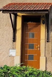 Porte d'entrée en bois avec poignée et décorations horizontales or, ainsi que deux carrés de verre au centre