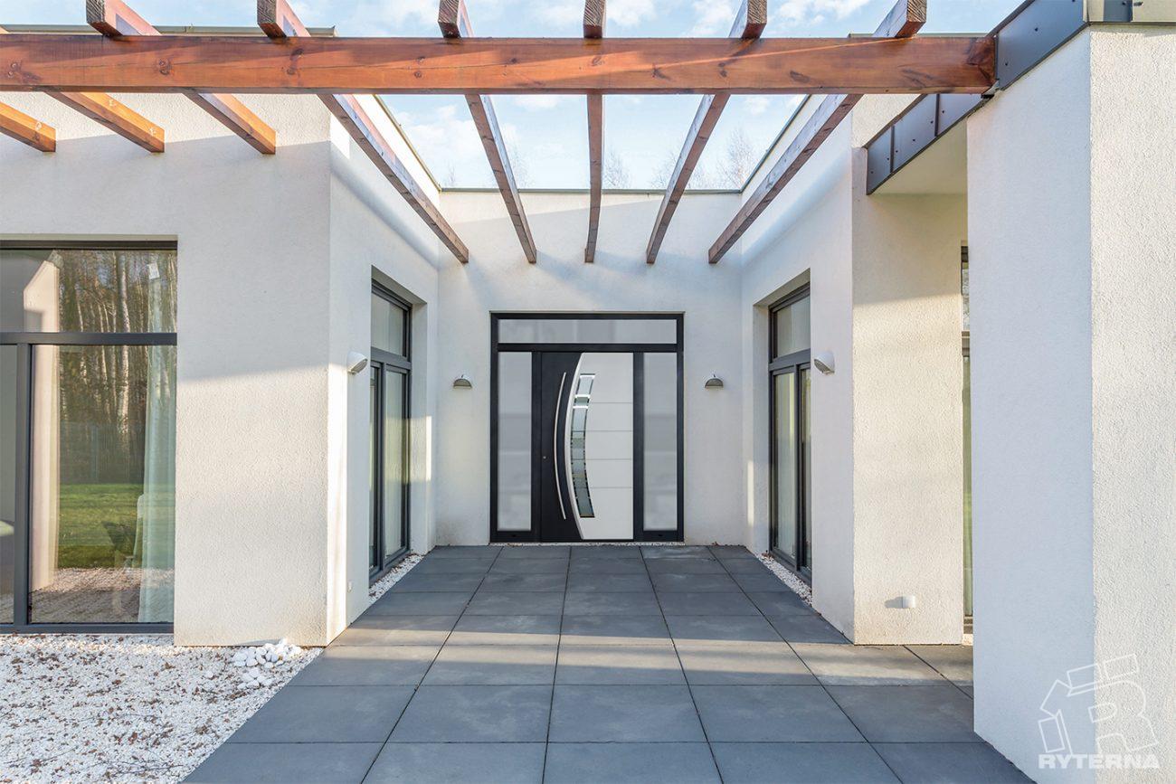 Hall d'entrée extérieur aves des menuiseries moderne dont une porte blanche avec des formes géométriques modernes.