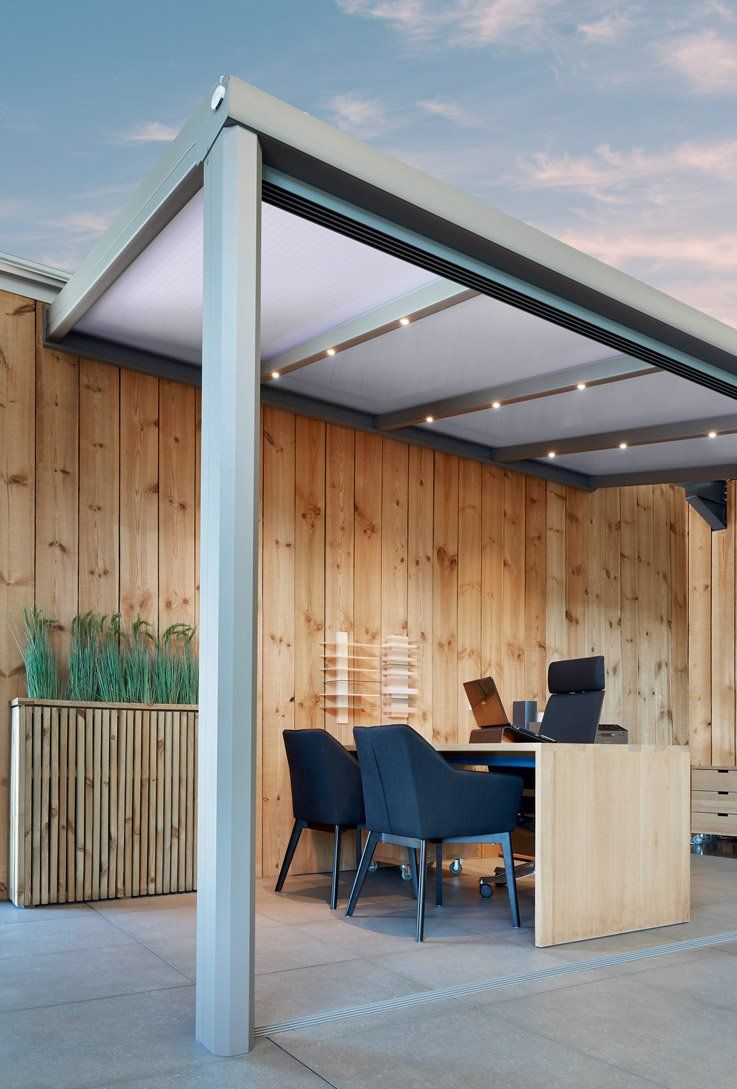 Pergola métallique claire avec luminaires au-dessus d'un espace extérieur revêtu de bois