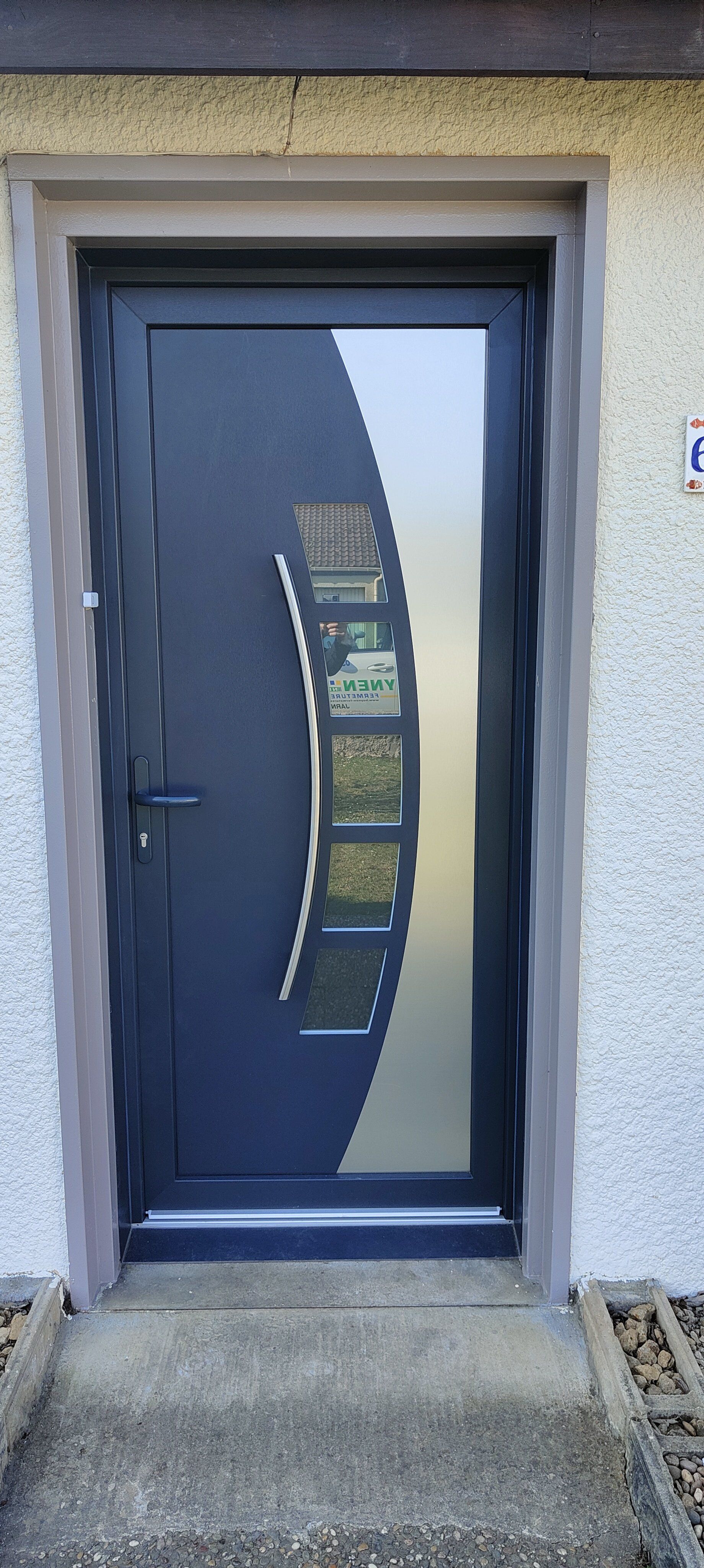 Porte d'entrée bleu sombre avec motifs géométriques arrondis en verre et métal