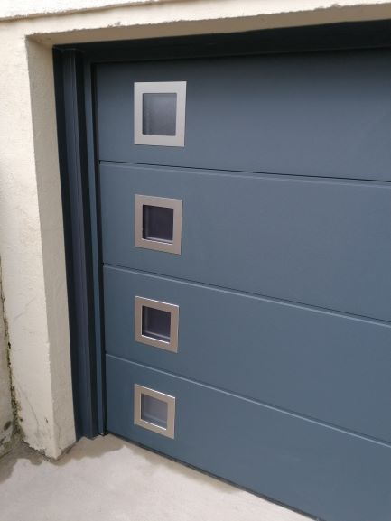 Porte de garage à bascule gris anthracite avec des petits carreaux opaques sur le côté tout le long