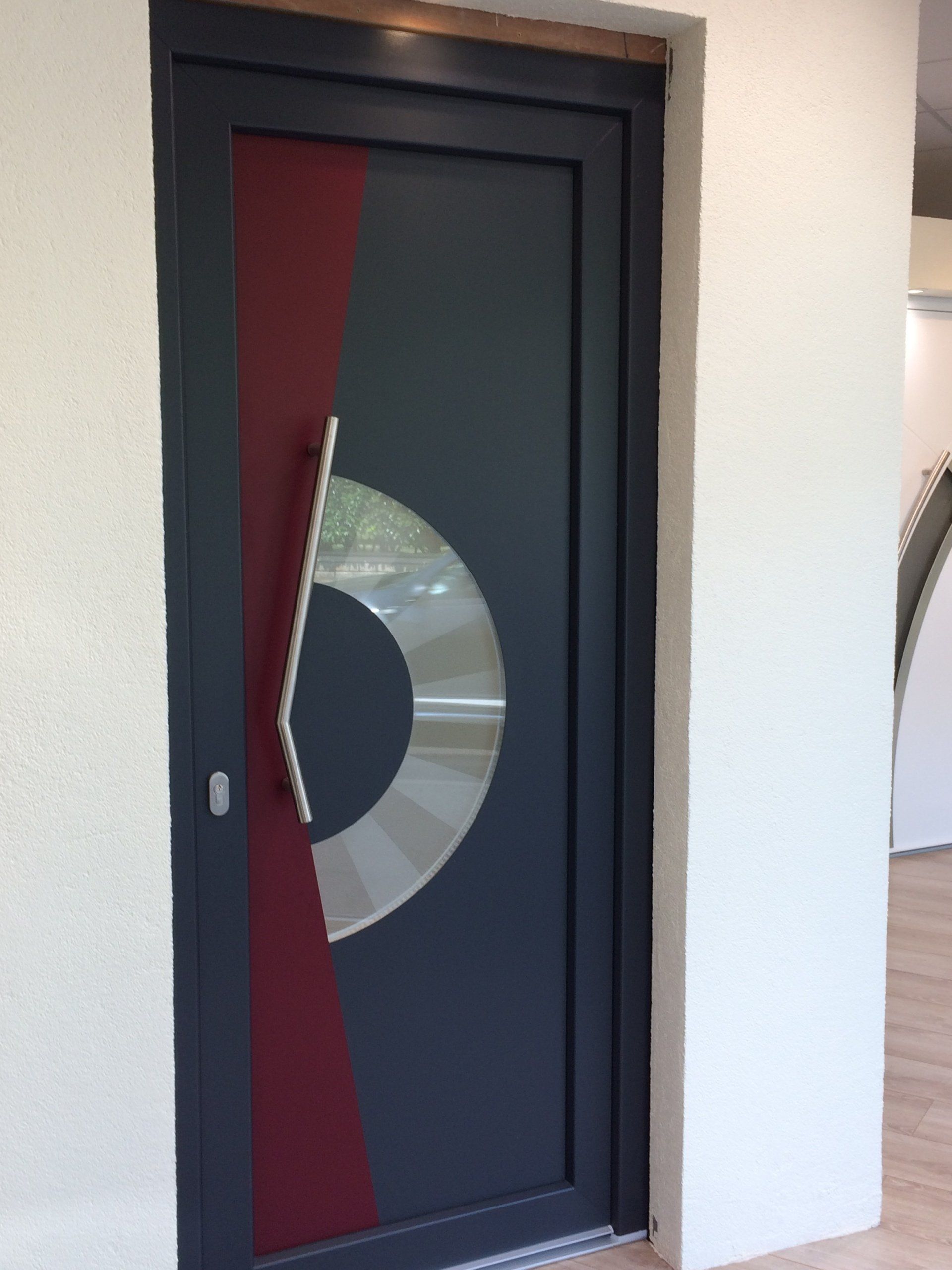 Porte rouge et grise avec des formes géométriques et poignée en acier inoxydable.