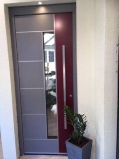 Porte d'entrée composée d'une partie rouge, d'une en verre et d'une grise avec séparations métalliques horizontales