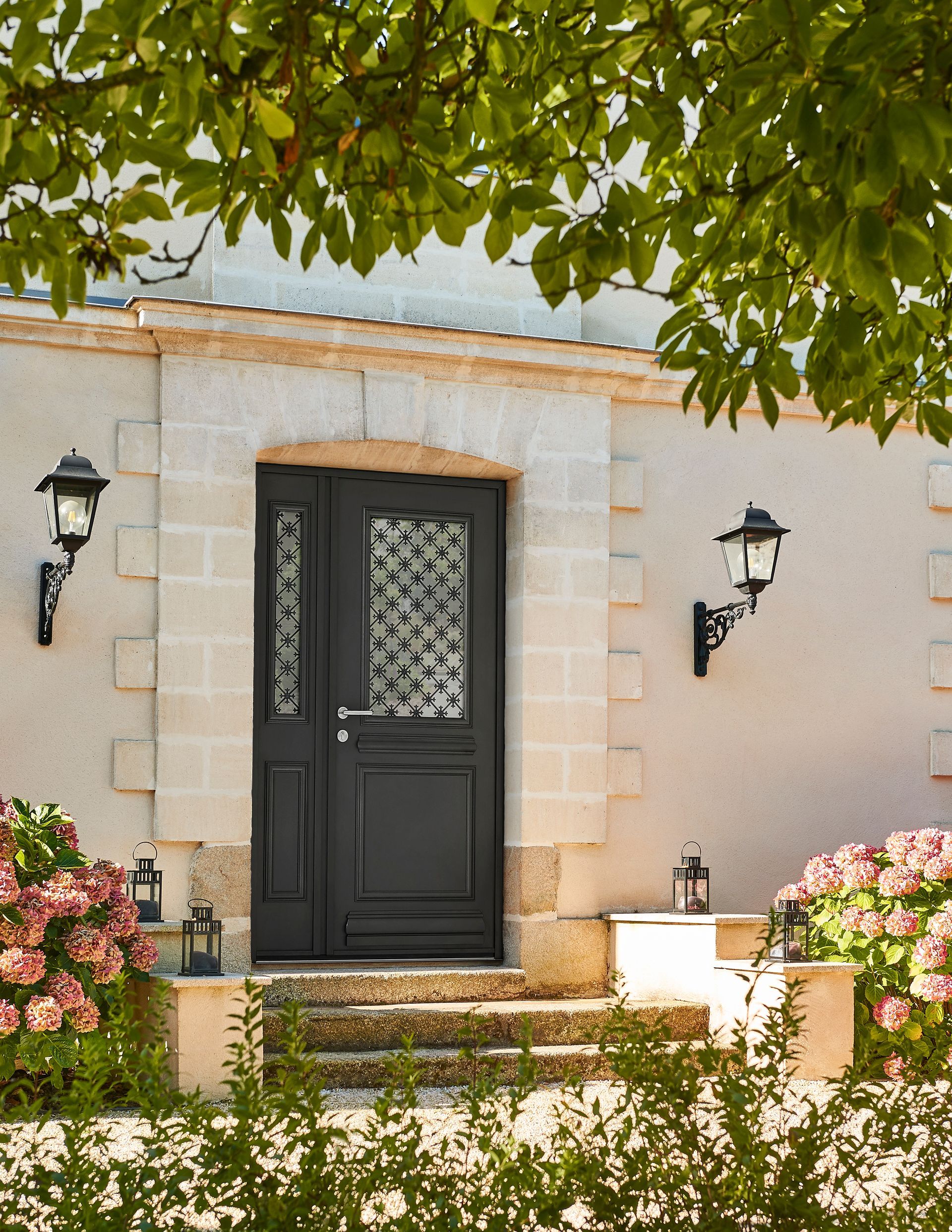 Porte d'entrée en aluminium et luminaires de chaque côté de l'entrée