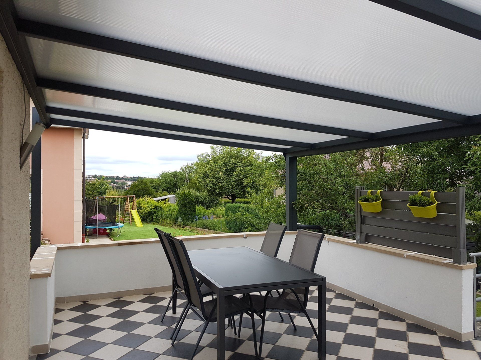 Pergola sombre avec panneaux clairs vue d'en dessous à côté d'une table et de chaises