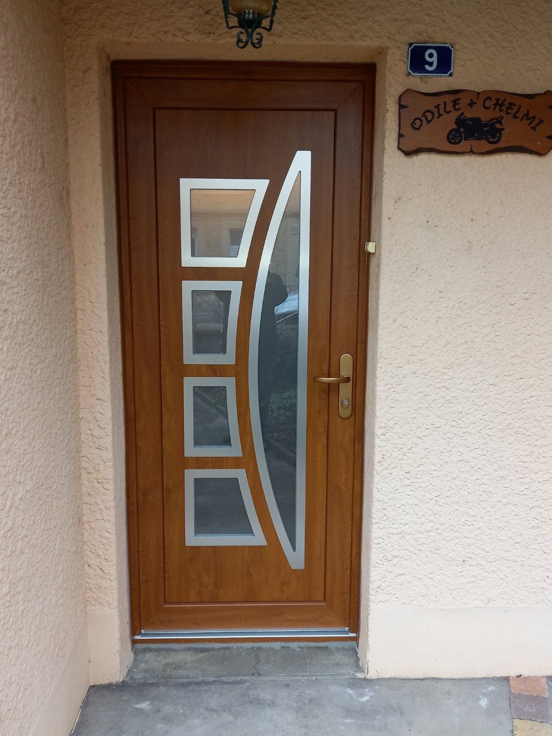 Porte d'entrée en bois avec motifs encadrés de métal et verre au centre