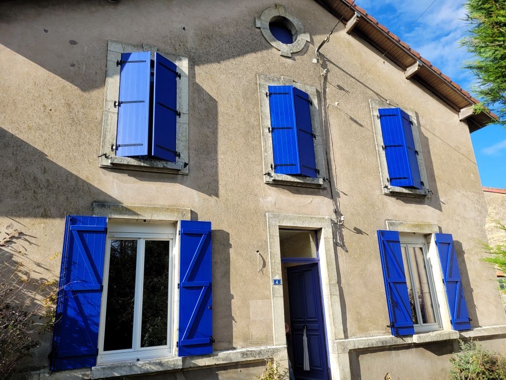 Volets bleus avec menuiseries blanches sur une grande façade de maison