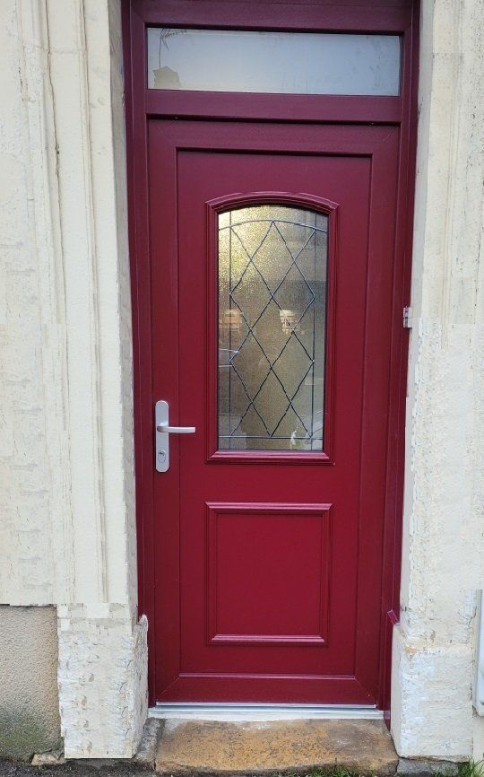 Porte d'entrée rouge en bois massif avec une finition élégante et des poignées en métal.