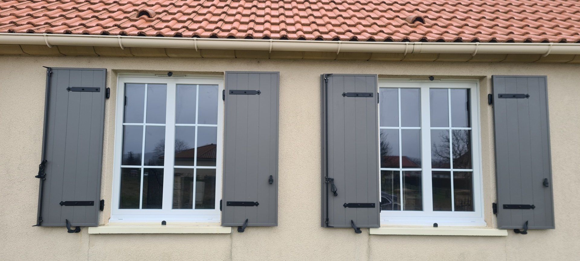 Façade de maison avec des volets de bois gris pour des menuiseries blanches