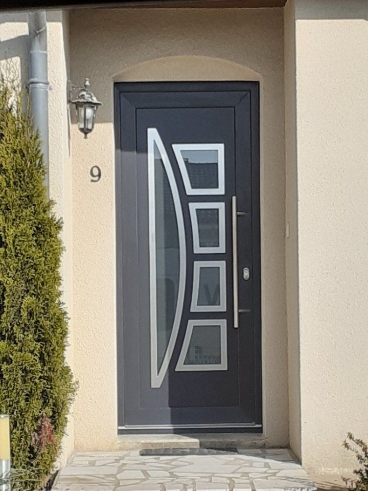 Porte noire en métal avec motifs géométriques et poignées en chrome.