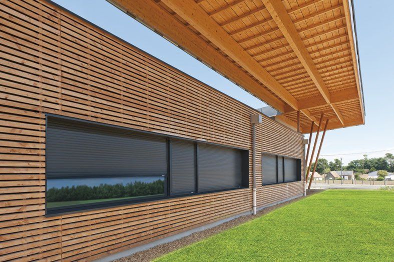 Longues fenêtres sombres en bâtiment avec bardage bois