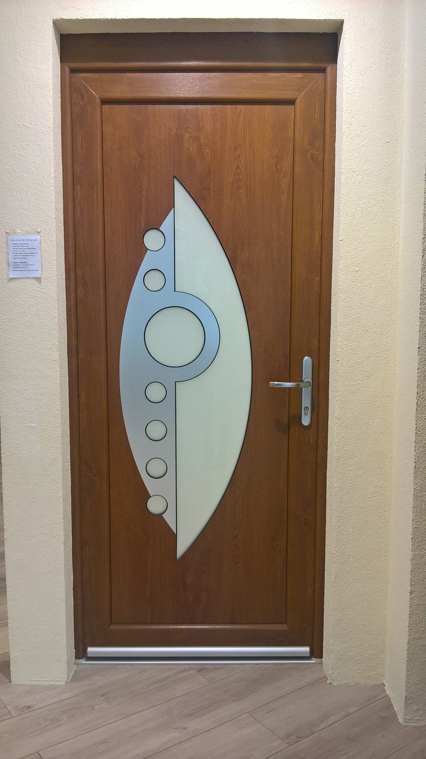 Porte d'entrée en bois avec au centre une forme ovale et des motifs métalliques ronds