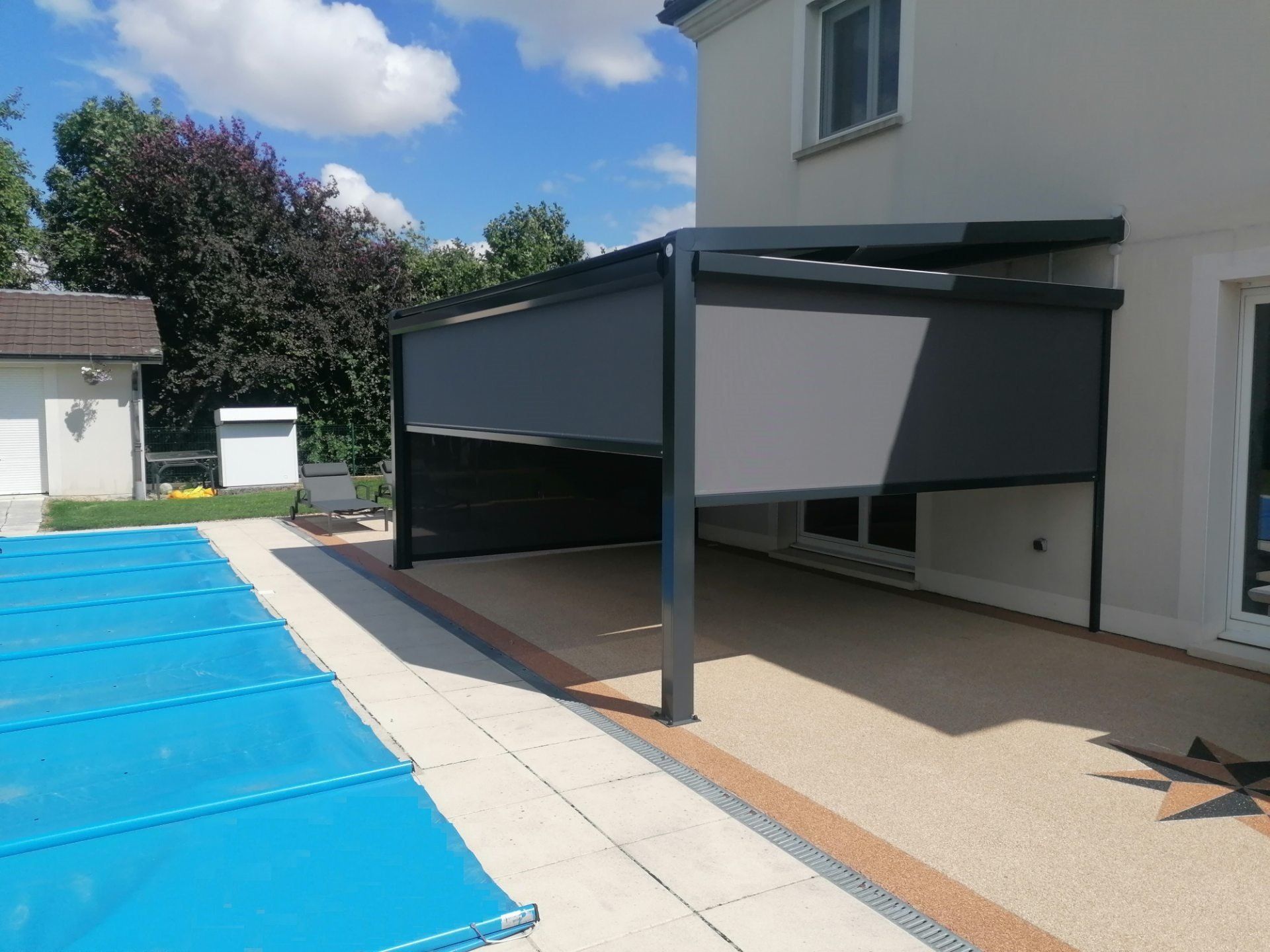 Pergola en aluminium noir avec des stores gris sur les côtés