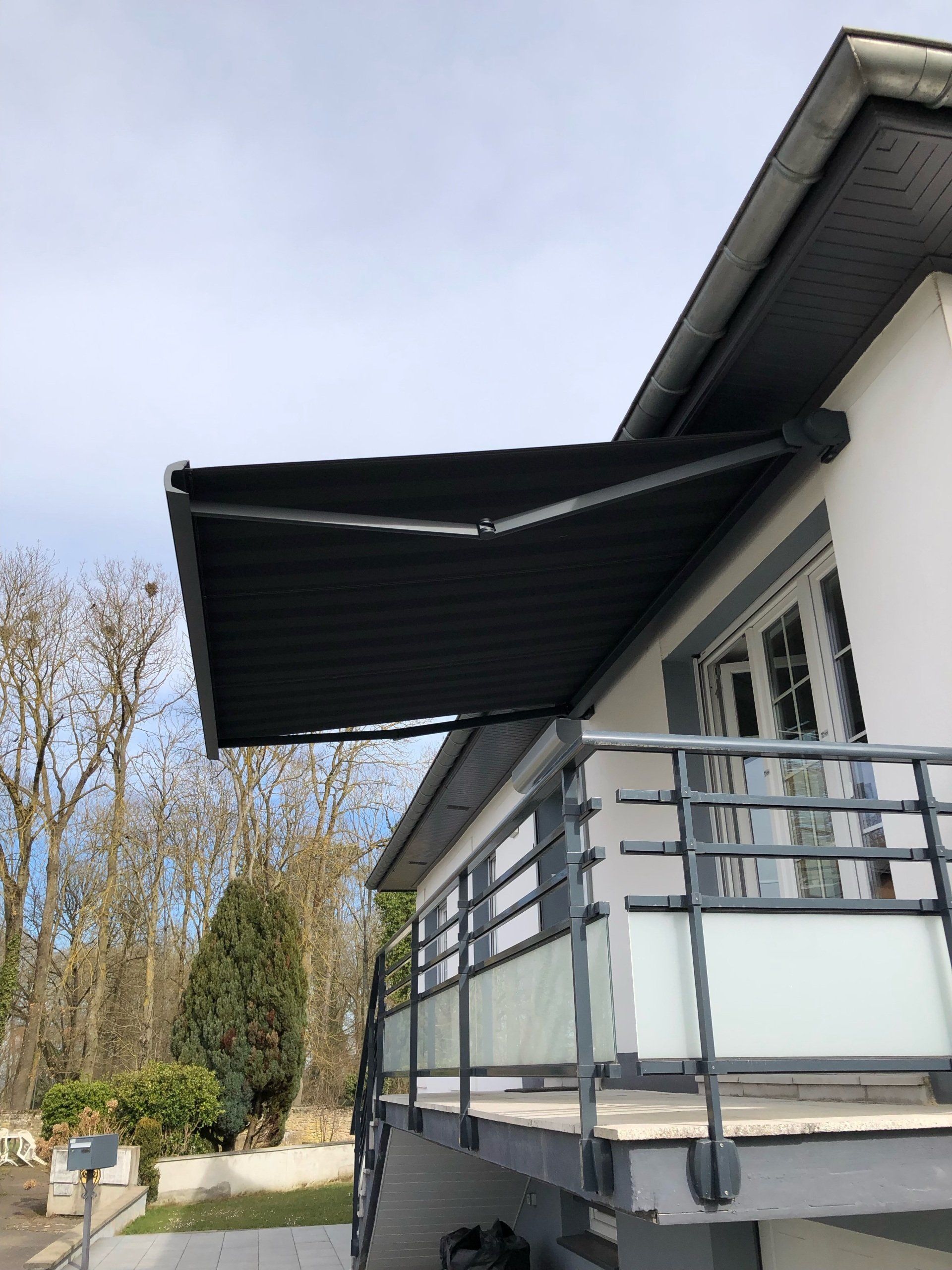 Store banne à toile sombre placé au-dessus d'un balcon d emaison