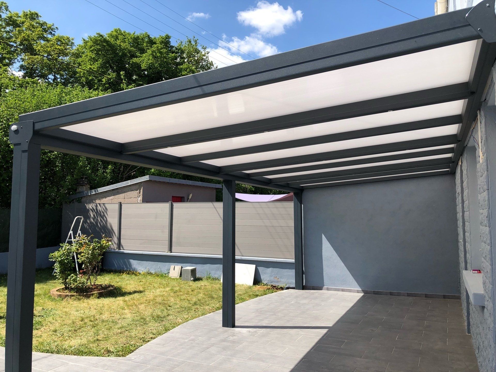 Pergola donnant sur le jardin et protégeant une terrasse en béton