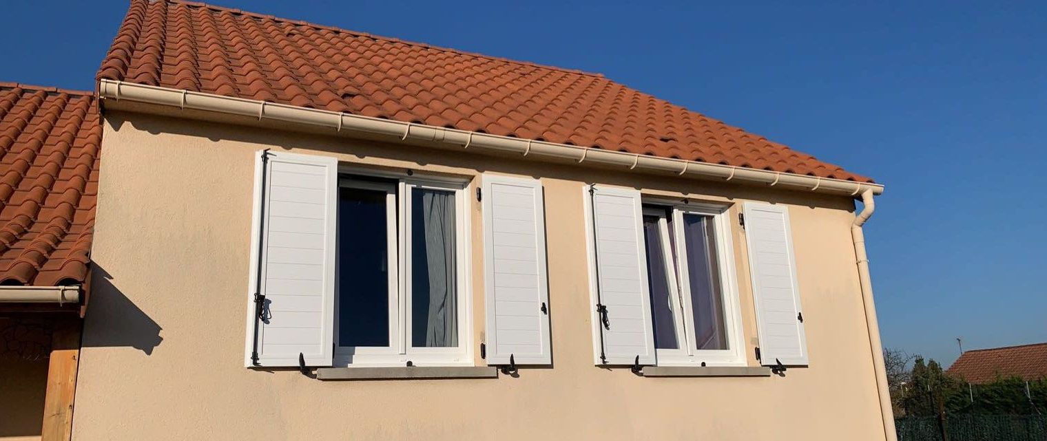 Volets de bois blanc sur une façade de crépis beige