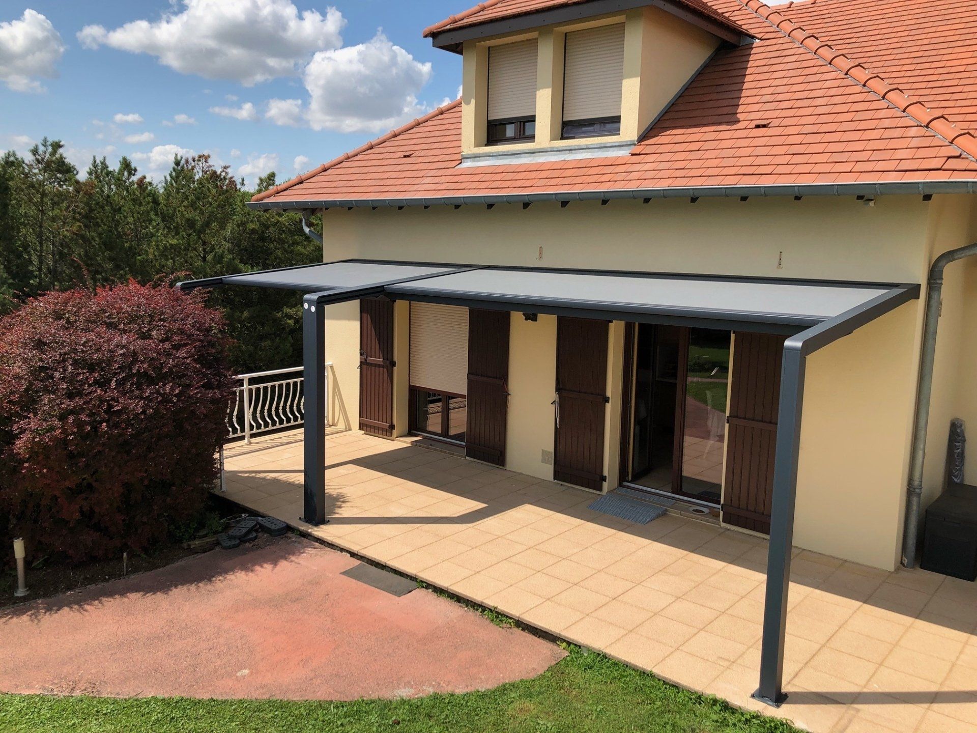 Pergola en aluminium noir avec stores bannes sur une terrasse en bois