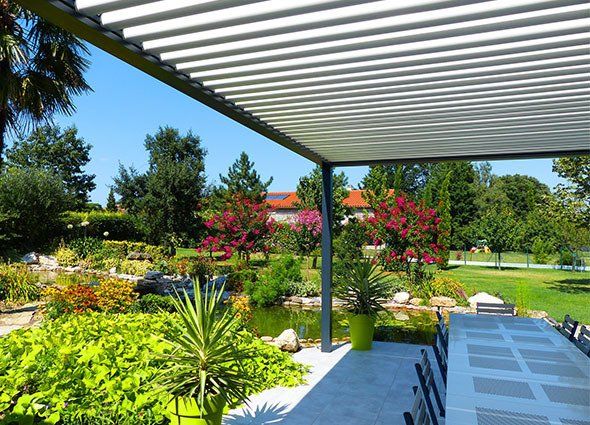 Pergola bioclimatique donnant sur un vaste jardin verduré