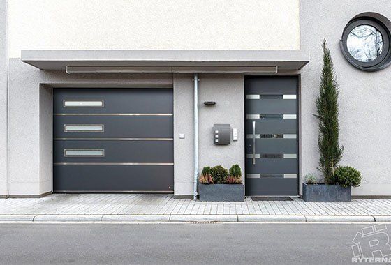 Porte de garage et porte d'entrée assortie en aluminium noir et séparation par des bandes de vitres 